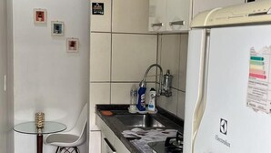 Cozinha com geladeira, pia e área de refeições com uma cadeira.