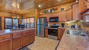 Une cuisine de style rustique, avec des éléments en bois, un îlot central, des appareils en acier inoxydable et des armoires en bois.