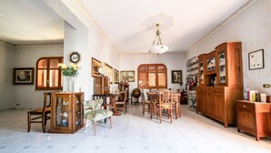 A spacious room with a dining area, wooden furniture, and a ceiling fan. - Il rifugio del templare  - Appartamento Cavaliere (Roccavaldina)