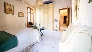 A bedroom with a bed, a chair, a wardrobe, a fan, and a mirror. - Il rifugio del templare  - Appartamento Cavaliere (Roccavaldina)
