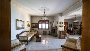 A spacious living room with a fireplace, multiple sofas, and a dining area with chairs and a table. - Il rifugio del templare  - Appartamento Cavaliere (Roccavaldina)