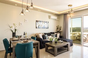 Un salon moderne avec un coin repas, comprenant un canapé, une table basse et une table à manger avec des chaises. Une grande fenêtre offre une vue sur l’extérieur.