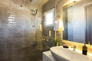 Une salle de bain moderne avec un grand miroir, un lavabo et une douche.