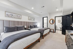 Una habitación de hotel moderna con dos camas, un espejo redondo y un aparador.