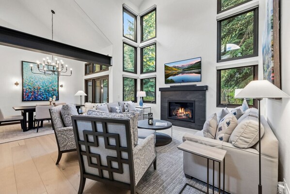 Una sala de estar moderna con chimenea, ventanas amplias y un comedor.