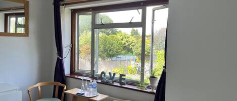 A room with a large window, two chairs, a small table with a tray of water bottles, and a radiator.