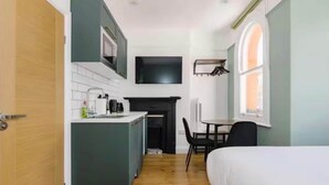 Habitación pequeña con kitchenette, cama y ventana.