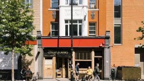 Ein zweistöckiges Gebäude mit roter Markise und einem Schild mit der Aufschrift 'Lincoln Arms'.