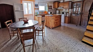 Une cuisine compacte dotée de meubles en bois, d’un îlot central et d’un coin repas avec des chaises.