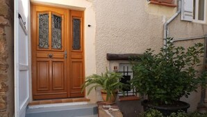 Une porte en bois avec un panneau de verre, un escalier en pierre et des plantes en pot.