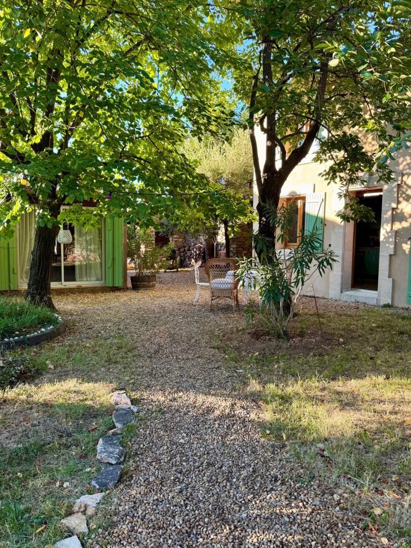 A courtyard with a gravel path, a chair, and a small table.