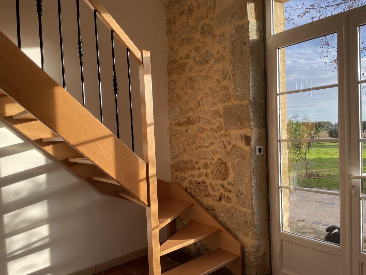 Eine Holztreppe mit einer Steinwand und einer Glastür, die nach draußen führt.