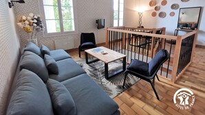 Ein modernes Wohnzimmer mit einer Couch, einem Couchtisch und einem Essbereich mit Holzwand.