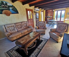 Una sala de estar con un sofá, sillones, una mesa de centro y una televisión.