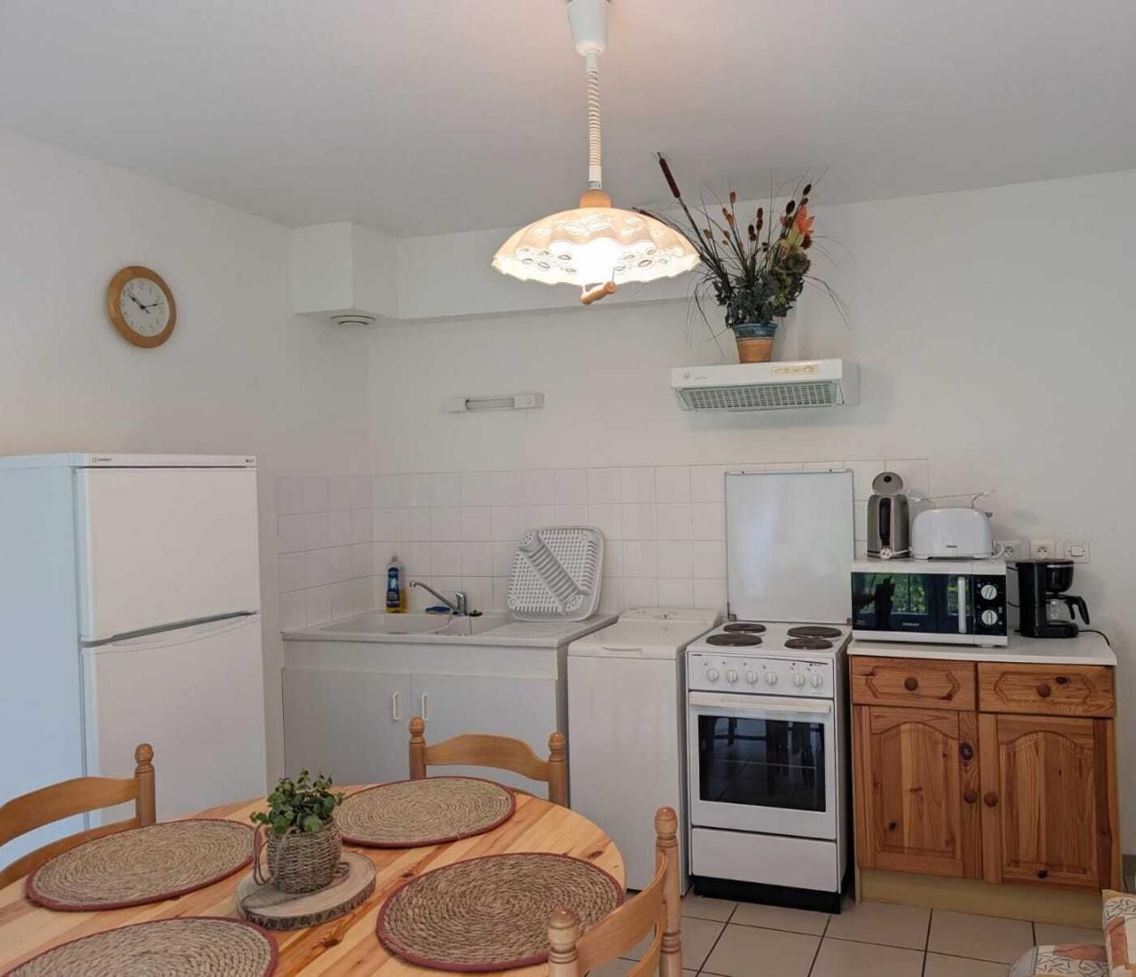 A kitchen with a refrigerator, stove, sink, and wooden cabinets.