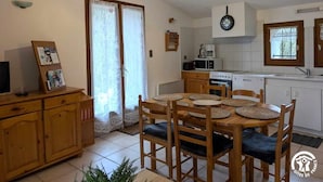 Cocina compacta con comedor, armarios de madera, un reloj y un ventilador de techo.