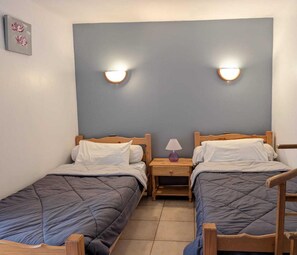 Quarto duplo com duas camas de solteiro, cabeceiras de madeira e mesas de cabeceira com abajures.