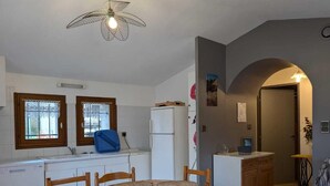 Cocina compacta con una mesa de comedor, sillas y un ventilador de techo.