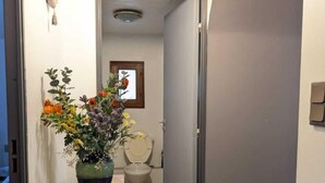 Un pasillo con una mesa de madera, una planta en maceta y un inodoro al fondo.