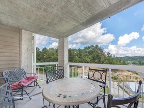 A covered outdoor seating area with a mosaic table and metal chairs, overlooking a natural landscape. - Two bedroom two bath condo| Pigeon Forge| Sleeps 4-6| City View (Pigeon Forge)