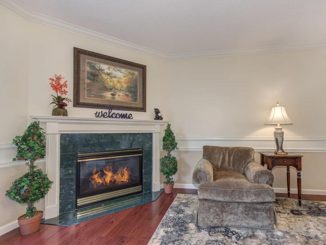 A living room with a fireplace, a sofa, a lamp, and a welcome sign above the fireplace.
