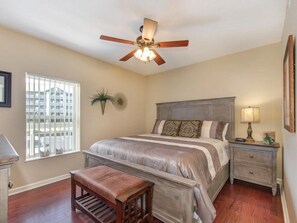 Un dormitorio con cama, mesita de noche, lámpara y ventilador de techo.
