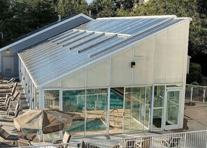 Een modern gebouw met een glazen gevel, een zwembadgedeelte en een overdekt terras.
