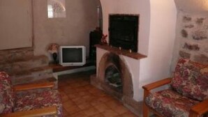 Un salon avec une cheminée, un téléviseur et deux fauteuils à motifs floraux.