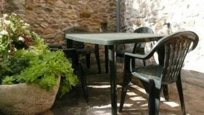 Une terrasse extérieure entourée de murs en pierre, avec une table et des chaises.