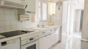 Una cocina con electrodomésticos blancos, un lavamanos, una estufa y un reloj en la pared.