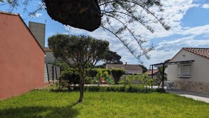 Un barrio residencial con un césped cuidado, un árbol y un edificio con techo de tejas.