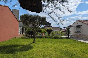 A residential area with a well-maintained lawn, a tree, and a building with a tiled roof. - Villa Joseph - AGDE - Gîte (AGDE)