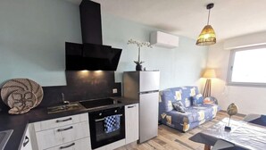 A compact kitchen with modern appliances, a dining area with a table and chairs, and a sofa.