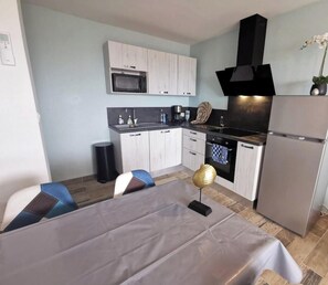 A modern kitchen with white cabinets, a black stove, and a stainless steel refrigerator.