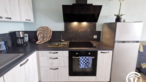 A compact kitchen with a black range hood, a built-in oven, and a white refrigerator.