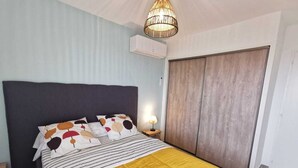 A bedroom with a bed, a bedside lamp, a wardrobe, and a hanging light fixture.