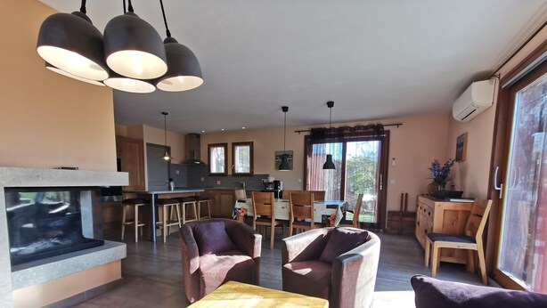 A modern living room with a fireplace, wooden furniture, and a large window. - Mas Le Bibane - BRENAS (BRENAS)