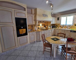 Une cuisine avec un mur recouvert de carreaux, une cuisinière et une table à manger avec des chaises.