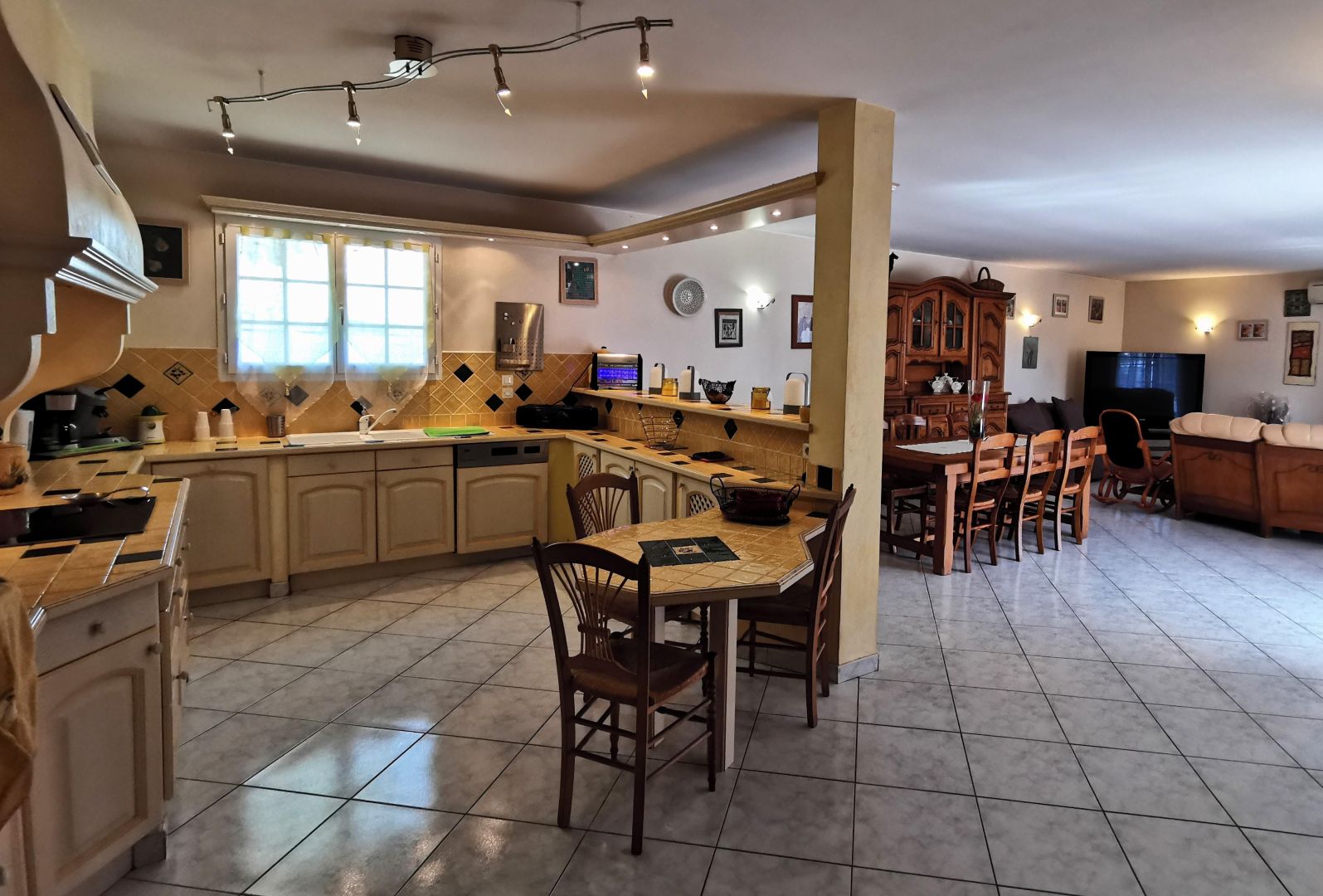 Una cocina amplia con comedor, que cuenta con una isla grande, armarios de madera y piso de baldosas.
