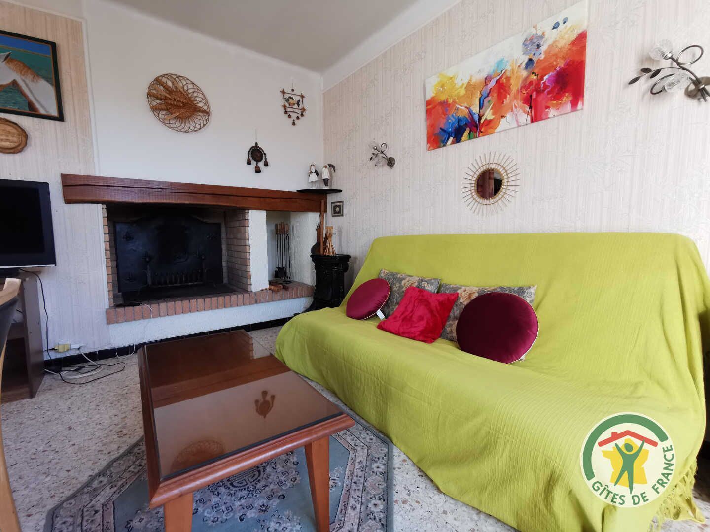 A living room with a green sofa, a fireplace, and various wall decorations.