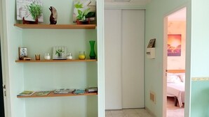 Ein Zimmer mit einem Bett, einer Tür zu einem anderen Raum und einem Regal mit Büchern und Dekoration.