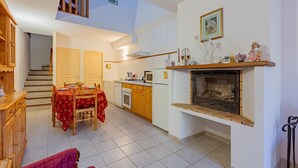 A compact kitchen with a dining area, a fireplace, and a staircase leading to an upper level. - La Bergerie - DIO-ET-VALQUIERES (DIO-ET-VALQUIERES)