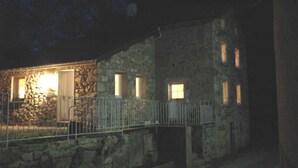A stone building with a metal fence, a door, and windows.