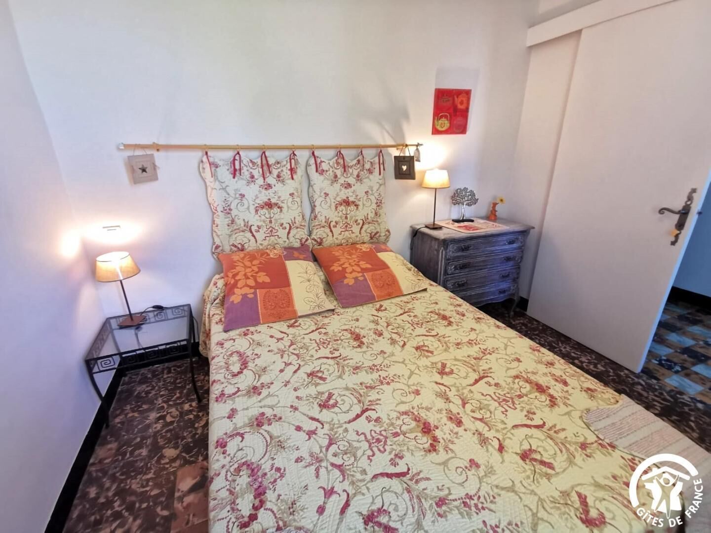 A bedroom with a bed, two bedside lamps, a nightstand, and a dresser.