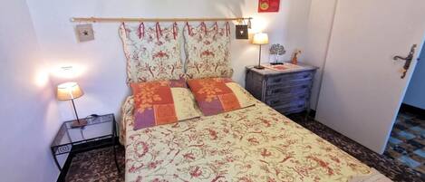 A bedroom with a bed, two bedside lamps, a nightstand, and a dresser.