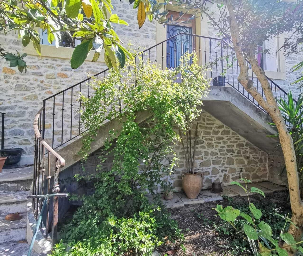 A stone staircase with a metal railing leading to a door with blue decorative elements.