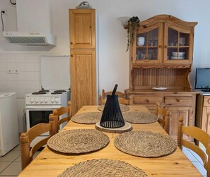 Una cocina con estufa, armarios y una mesa de comedor con individuales.