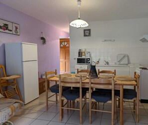 Cocina compacta con comedor, que incluye refrigerador, microondas, estufa y una mesa de comedor con sillas.