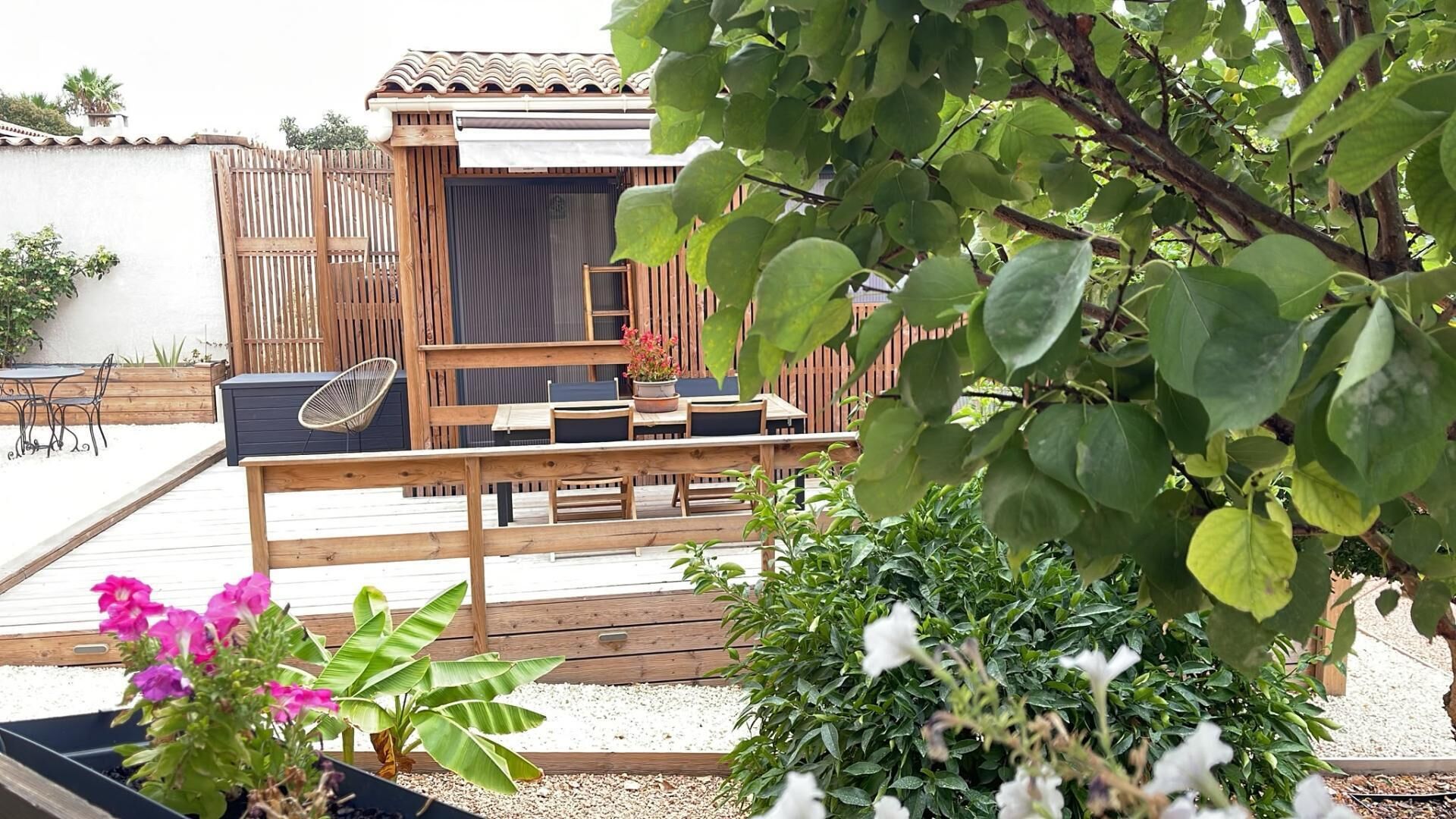 An outdoor patio area with a wooden deck, seating arrangements, and potted plants.