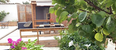 An outdoor patio area with a wooden deck, seating arrangements, and potted plants.